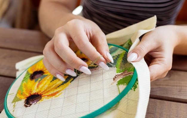 Mâini brodând detaliu floral